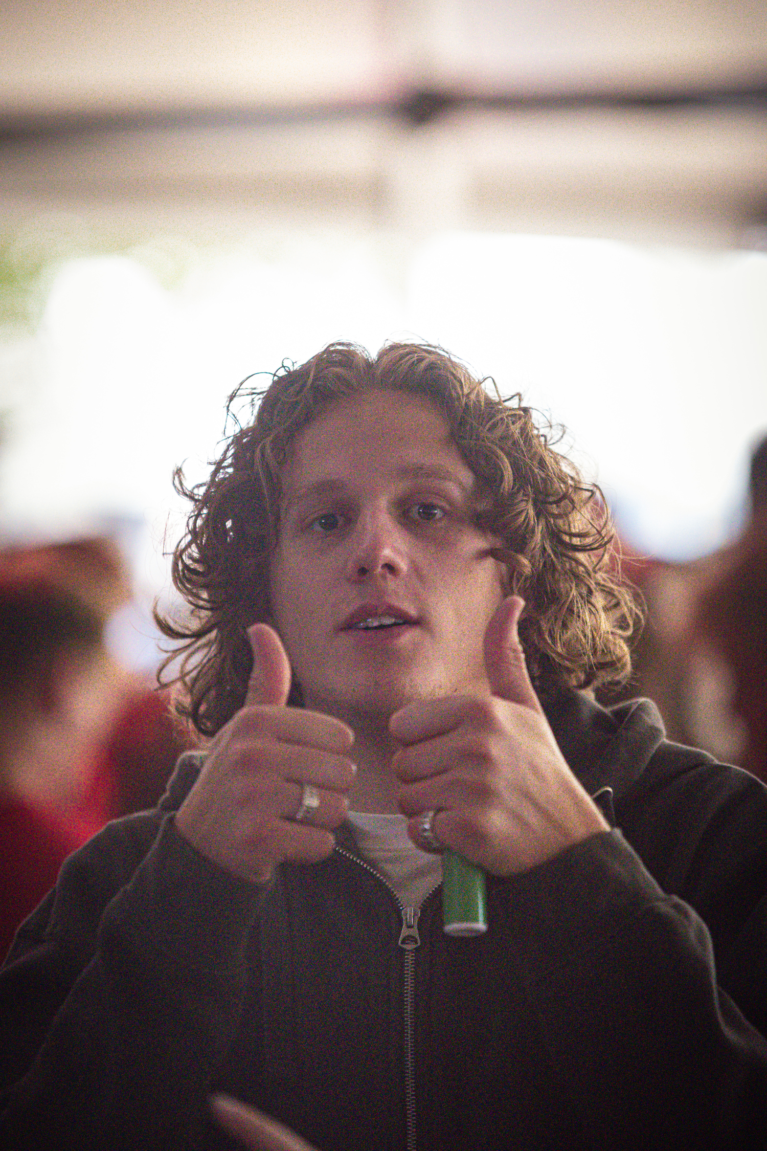 A person is giving a thumbs up while wearing a black jacket.