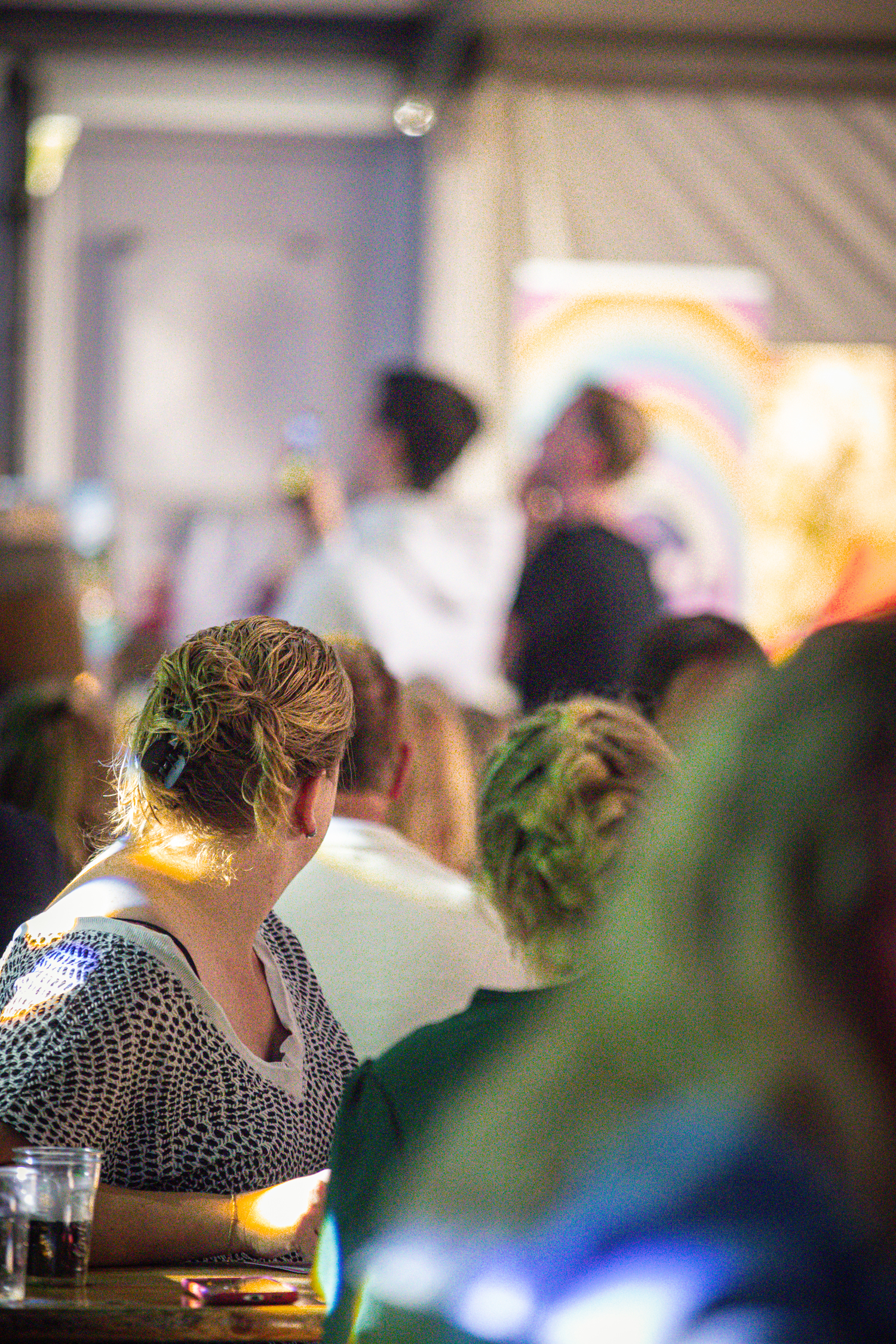 A person with a flower in their hair sits at the Kermis Boerhaar, watching a performer.