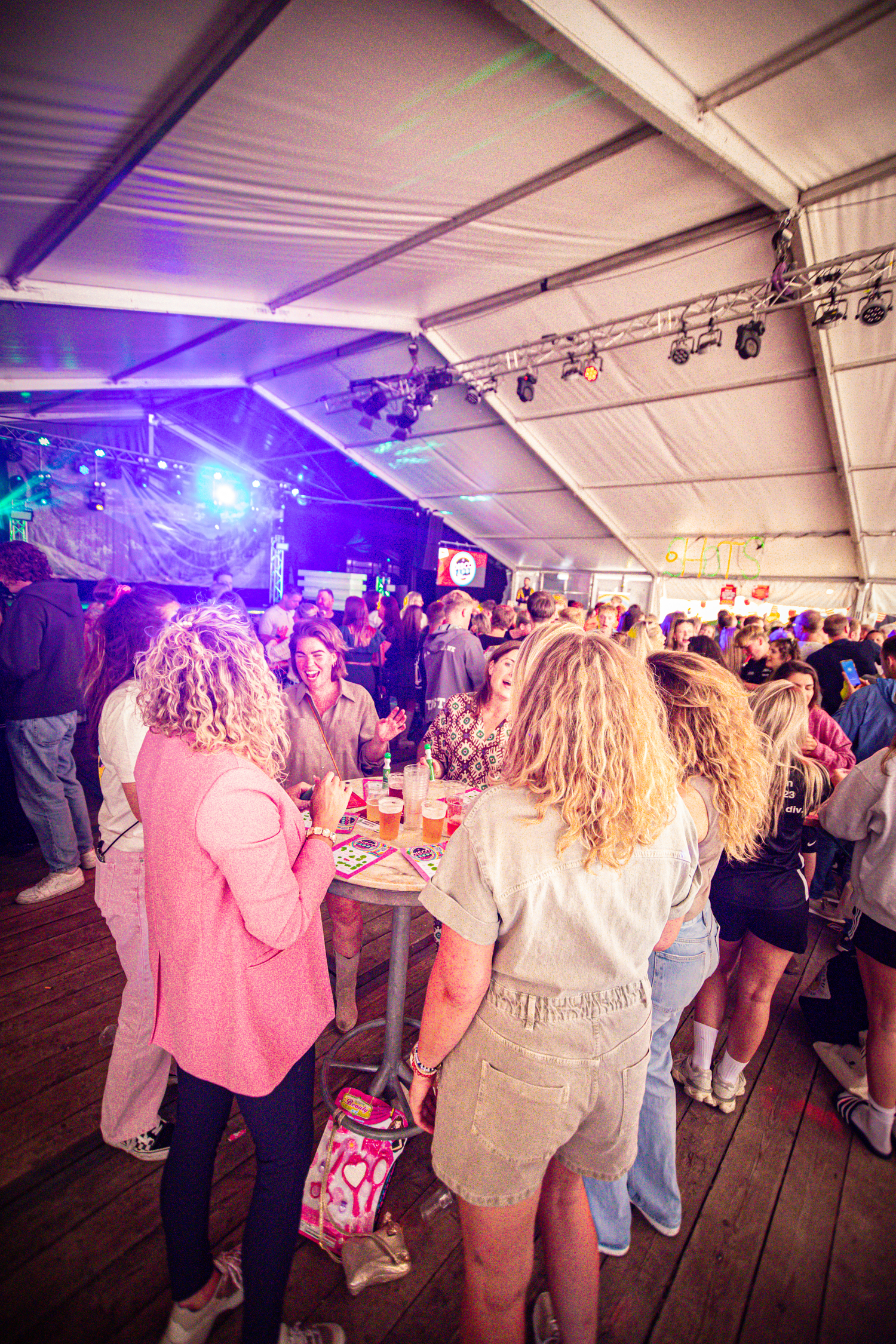 A crowded room at a Kermis Boerhaar event, with people enjoying drinks and snacks.