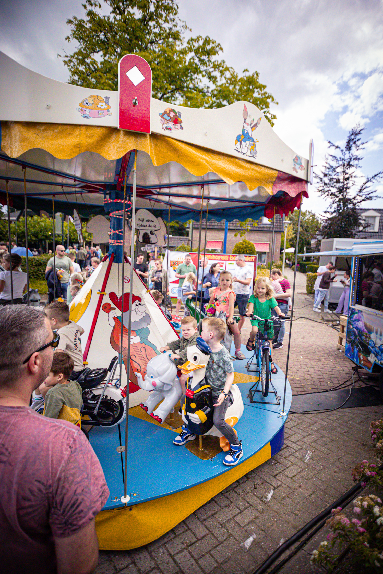 A group of people are gathered around a circus tent with children playing in the center.