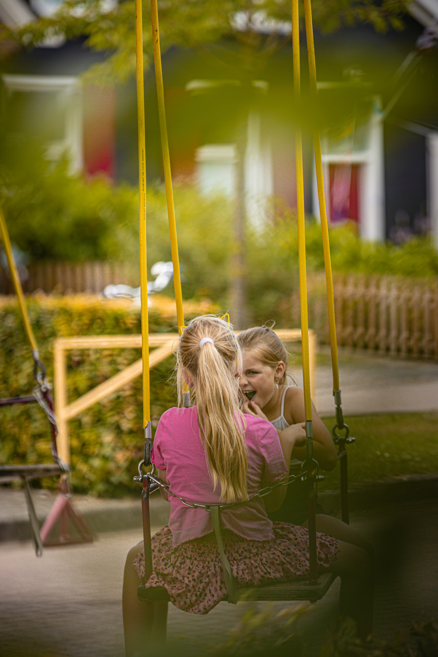 Two girls on a swing ride, one of whom is wearing a pink shirt.