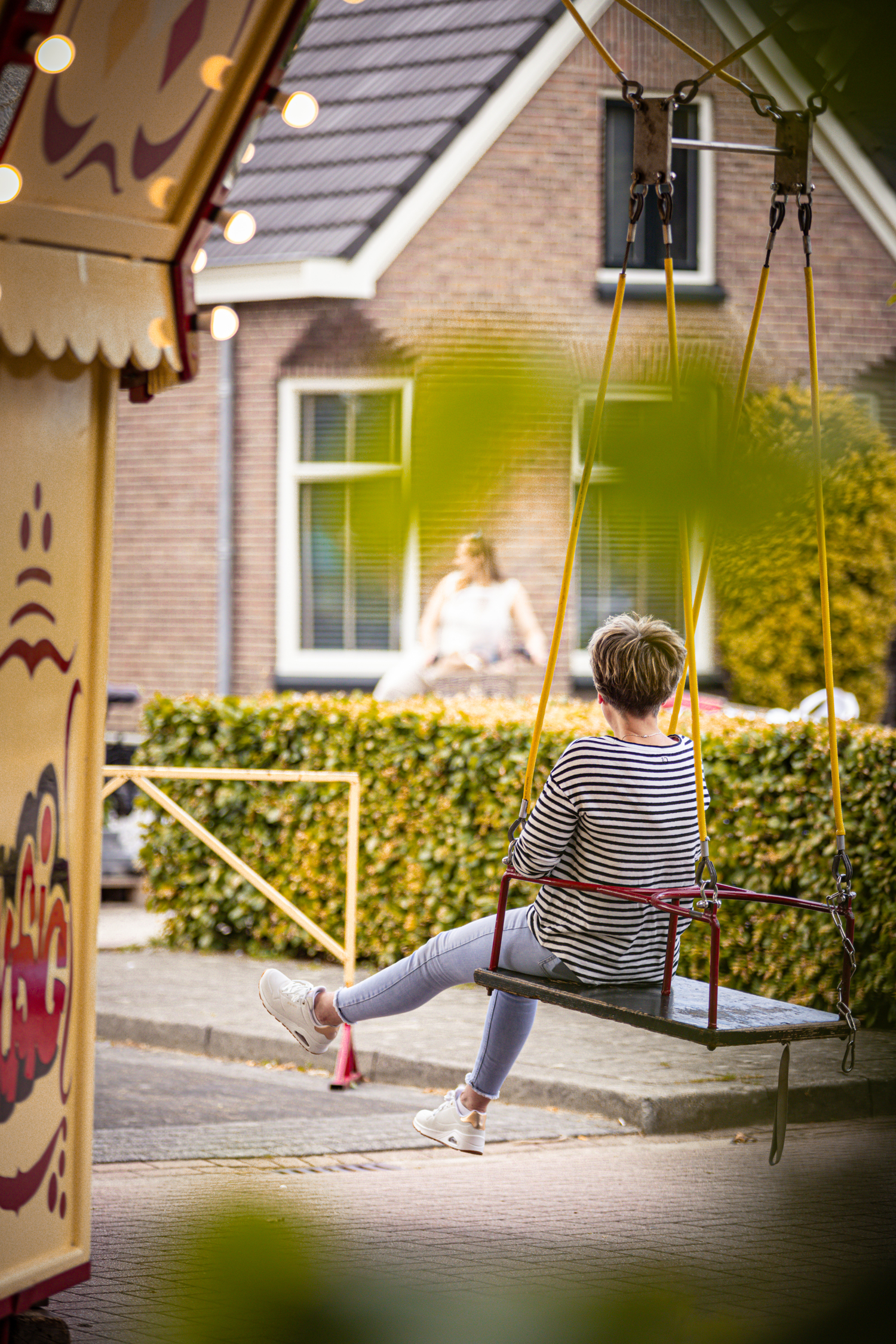 A person is sitting on a swing at an outdoor event called Kermis Boerhaar.