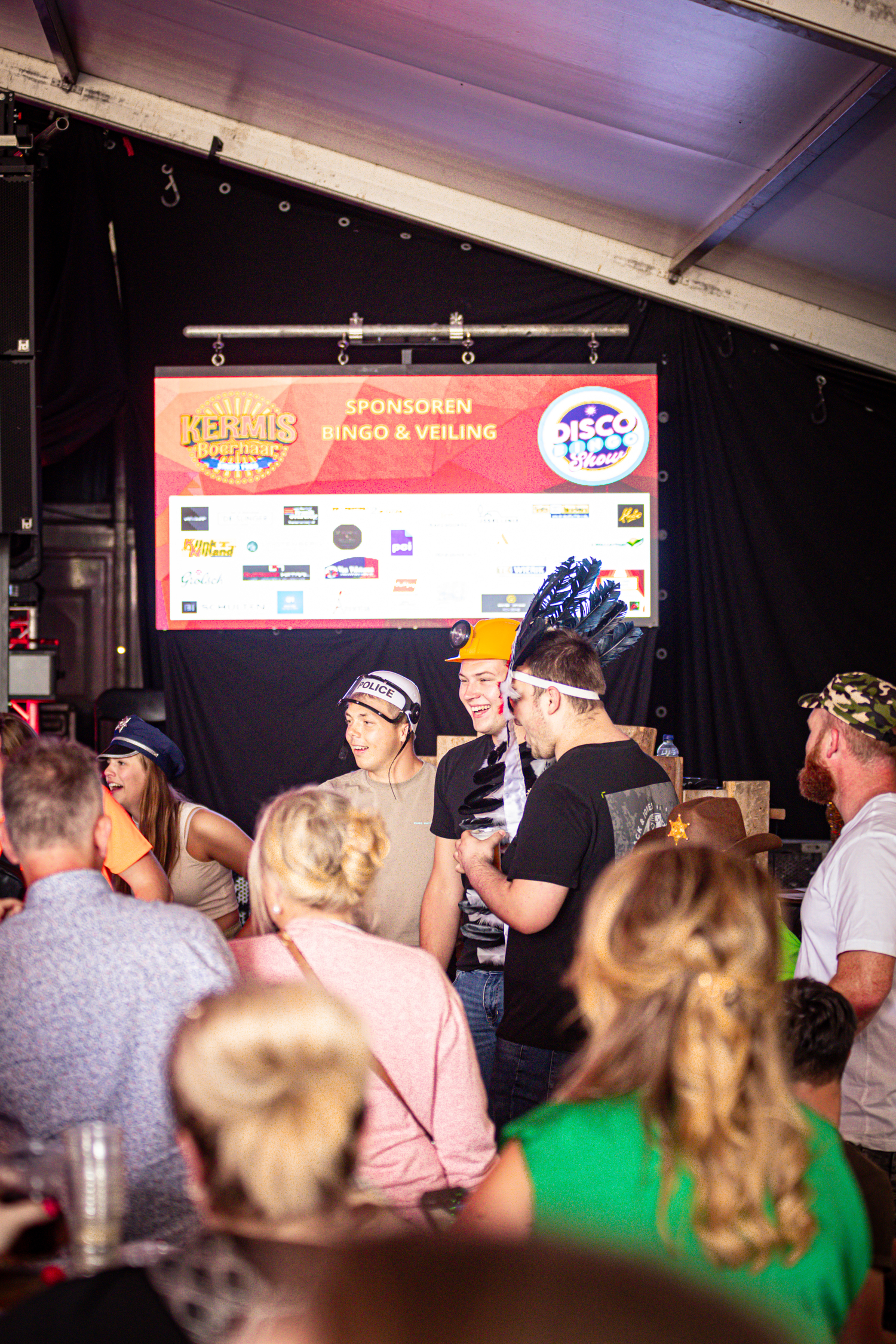 People standing around a stage with a sign that says "Kermis Boerhaar Middag & Avond".