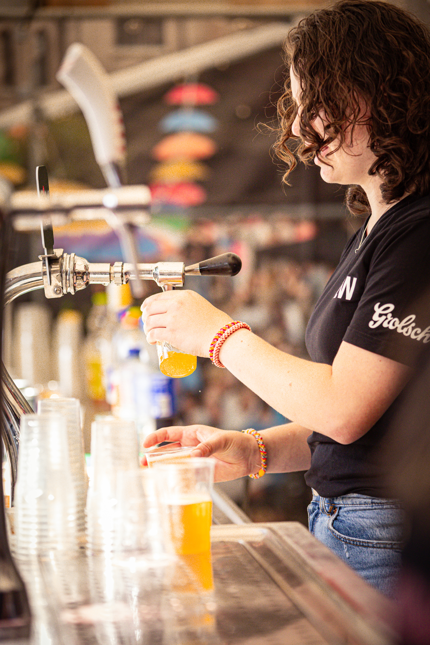 A woman pouring orange juice into a clear plastic cup.