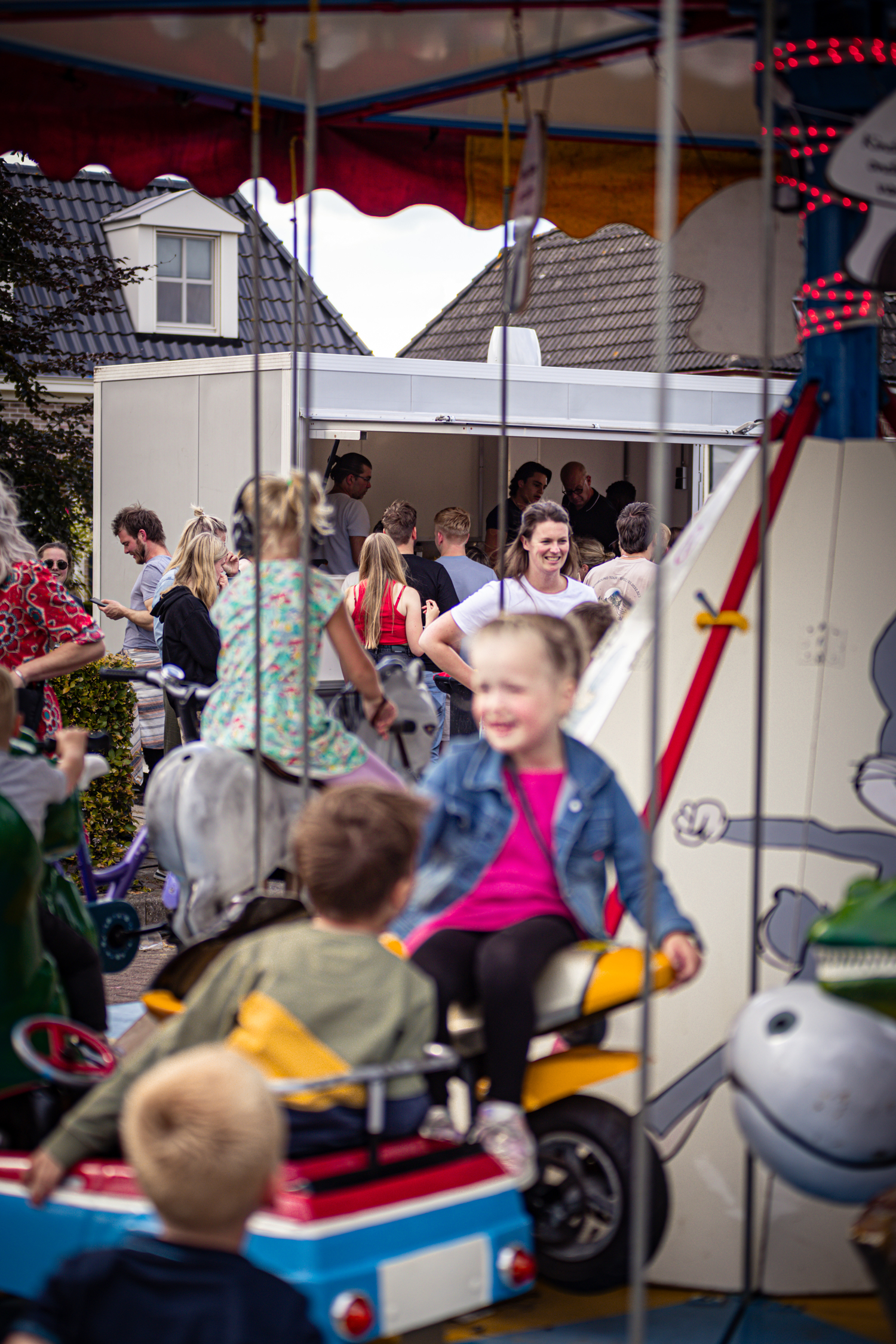 A carnival game with a carousel and several children, including one wearing a blue denim jacket.