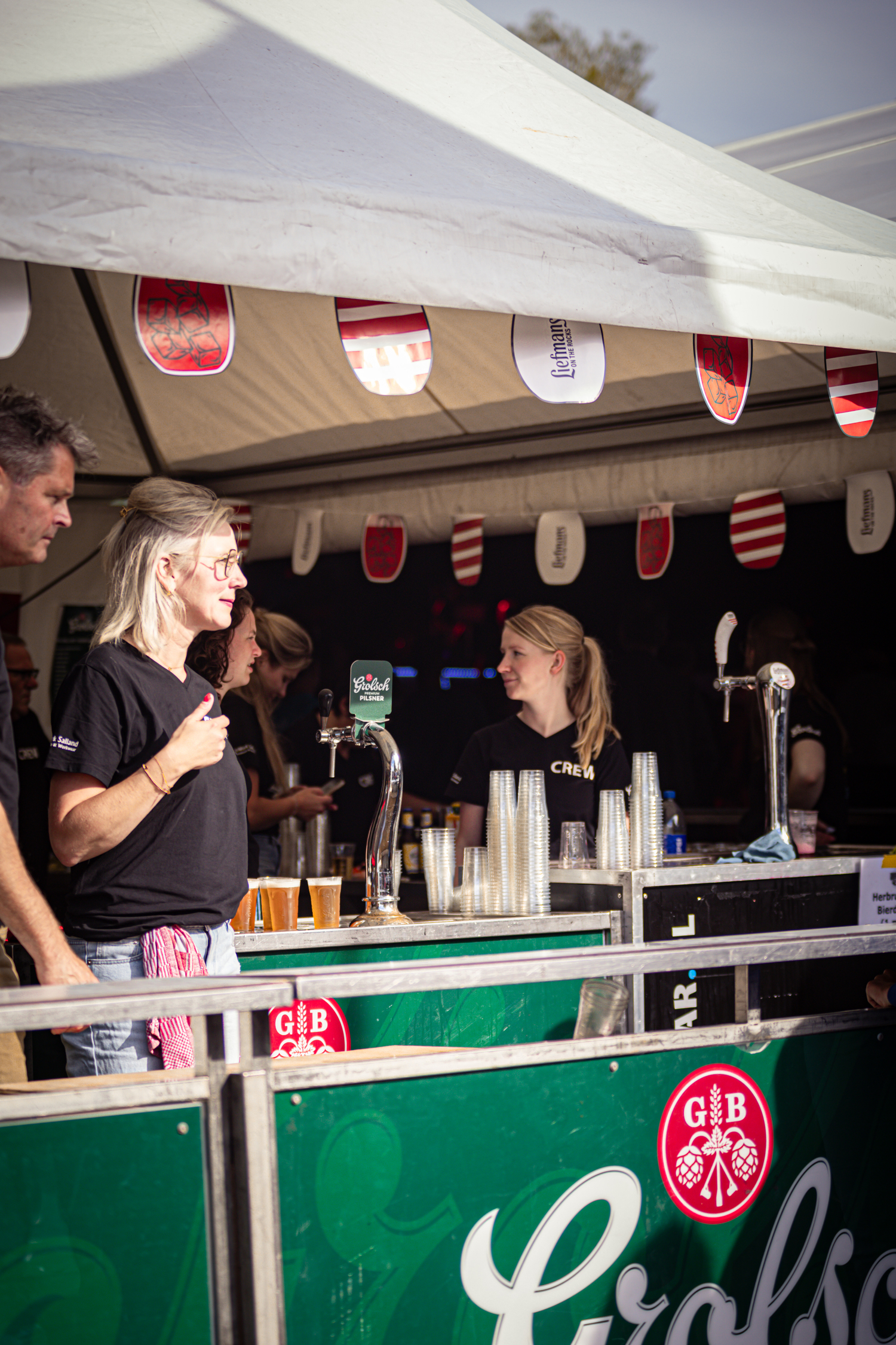 A woman standing at a counter, the counter has an advertisement for Kermit Boerhaar on it.