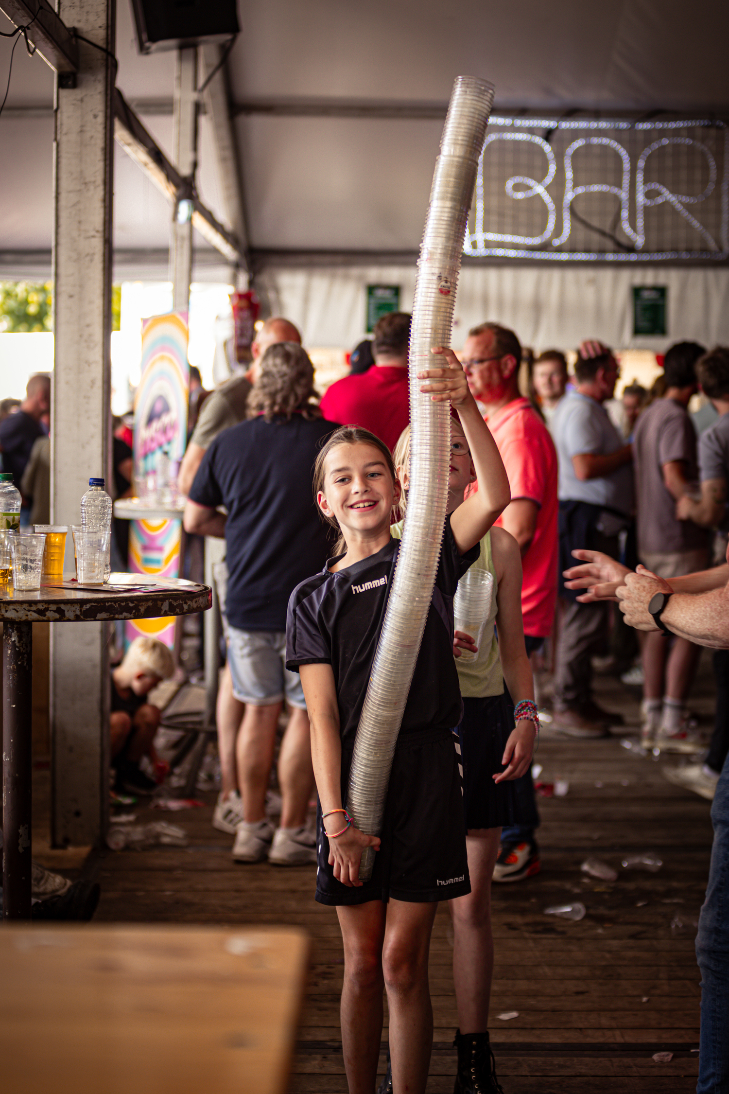 A young girl in a blue shirt holds up two paper tubes.