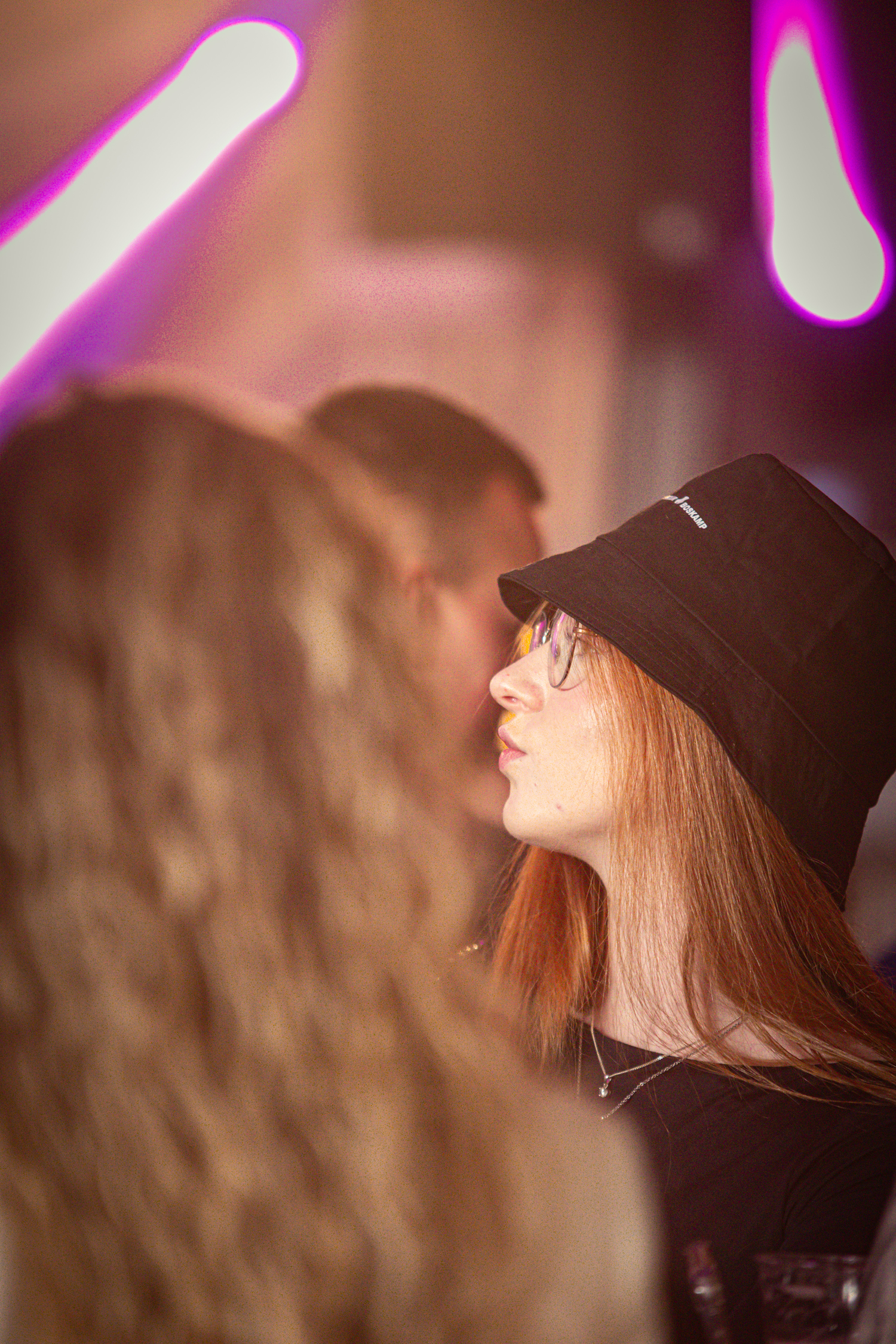 A woman in a black shirt is wearing a black hat that has the letters "G" and "M". She is looking to her left.