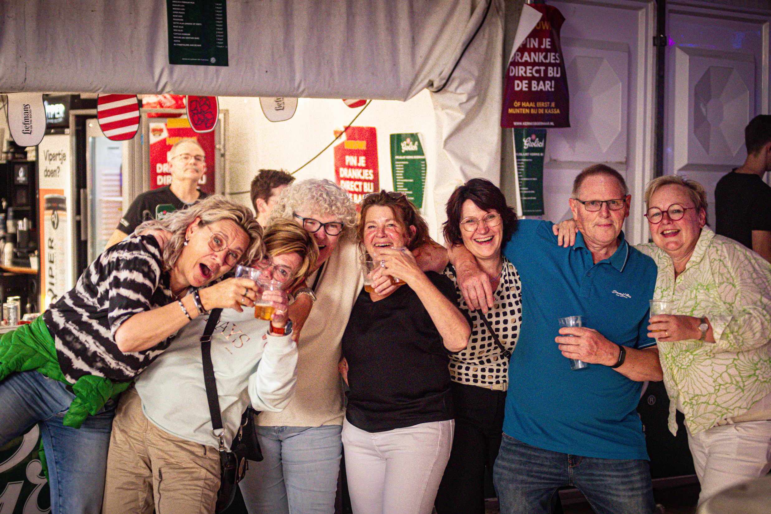 A group of people pose for a photo in front of a Kermis Boerhaar sign.