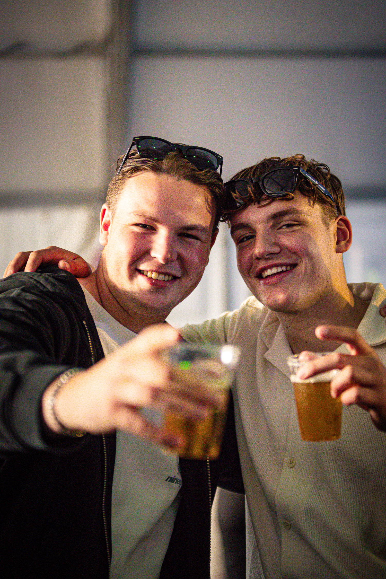 A young man is wearing sunglasses and holding a beer.