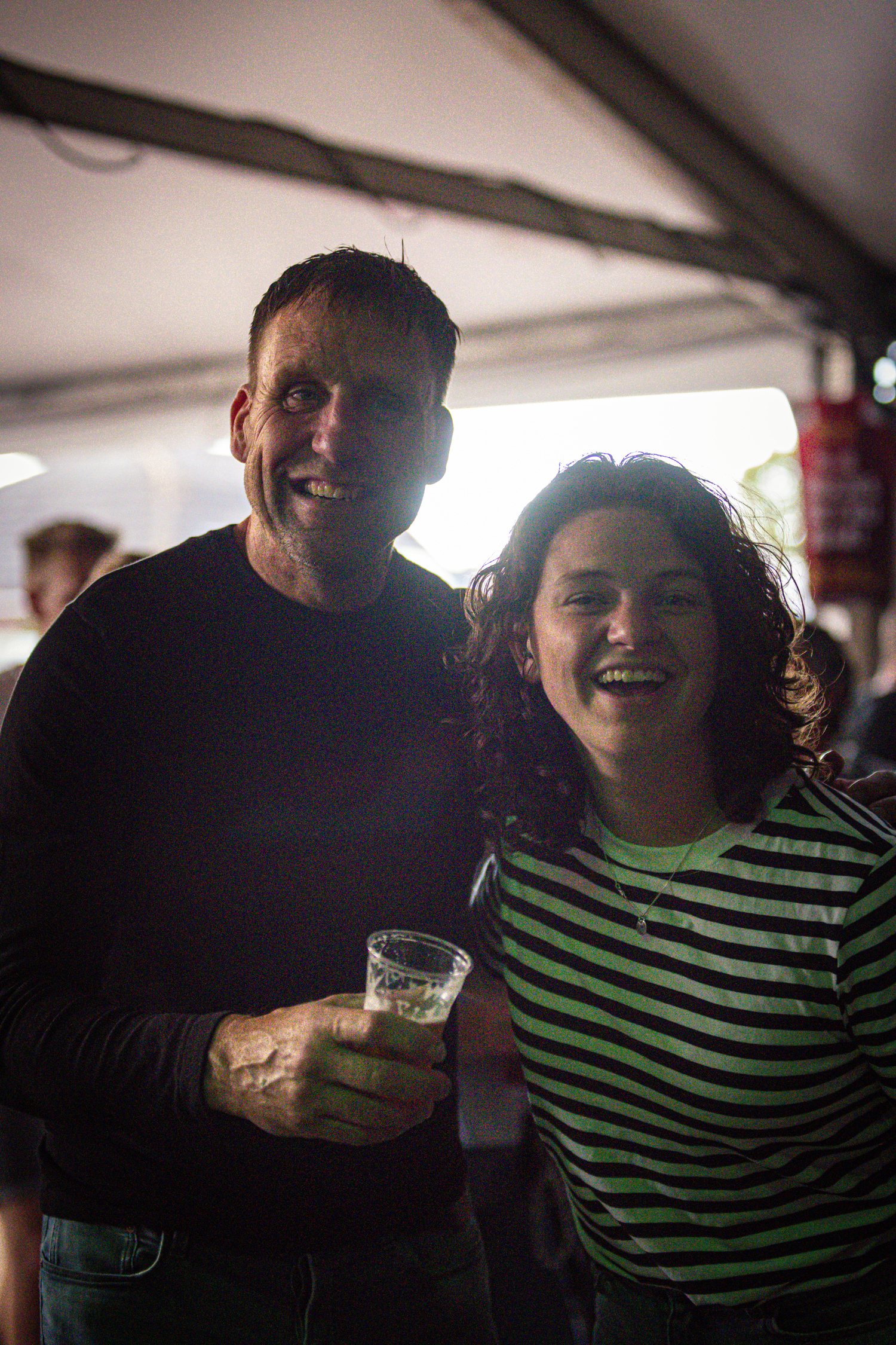 Two people enjoying themselves at a kermis. The man is holding a glass of beer in his hand, which has the letters "BRO".