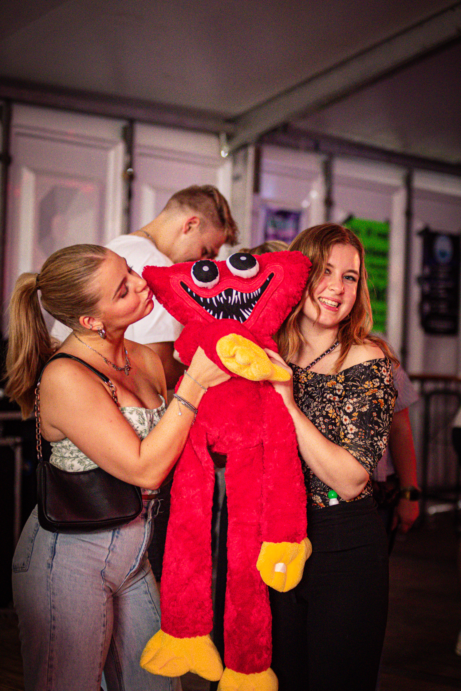 Drie meisjes houden een rood en geel stuffed dier in hun handen.