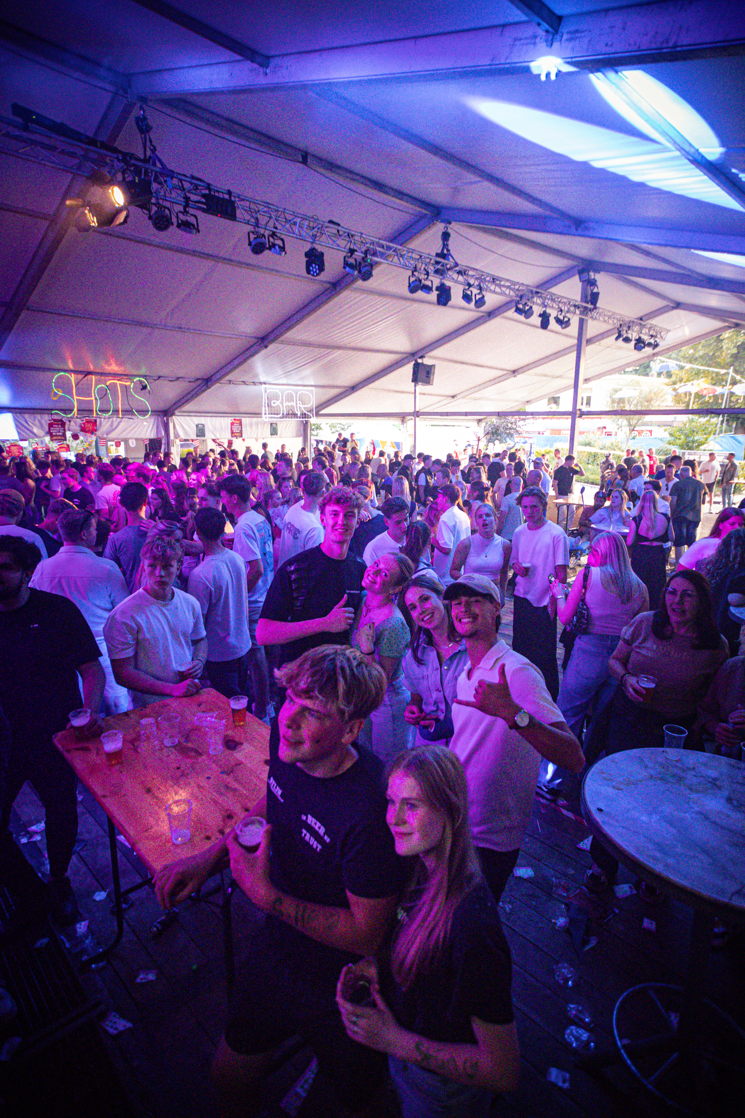 A group of people standing at a bar, drinking and laughing together. The atmosphere is lively and fun.