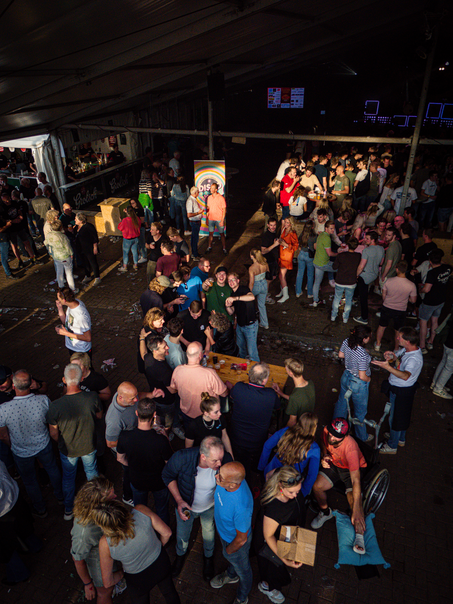 A lively scene at a carnival where people are gathered around tables, socializing and enjoying the event.