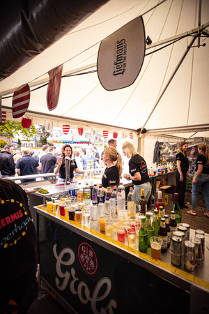 A tent is set up with a counter that has many bottles on it.