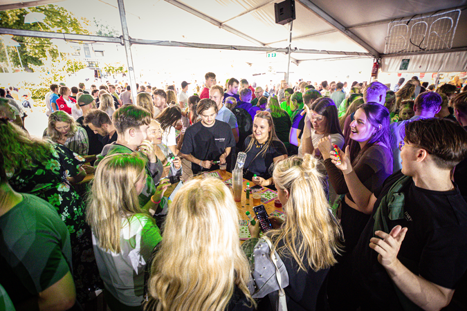 A group of people gathered in a tent, with the word "Kermis" written on it.