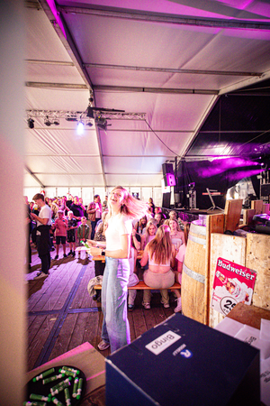 a Kermis Boerhaar gathering of people with a stage and purple lighting.