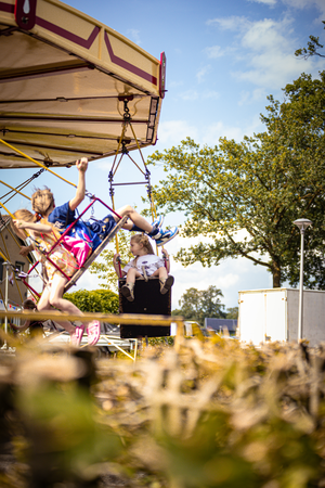 A woman and child are on a playground swing set with two other children.