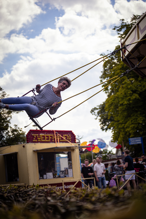 a lady on a seesaw in the middle of kermis boerhaar, and some people standing near it.