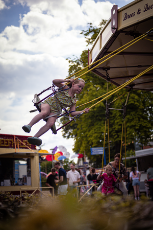 A young girl is swinging on a large yellow swing at a carnival.