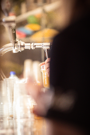 A close up of a bar tender pouring an alcoholic drink.