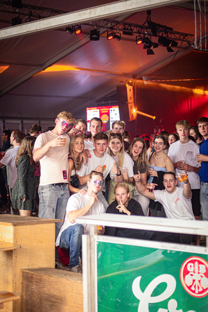 A group of people in a circus tent, enjoying themselves with drinks.