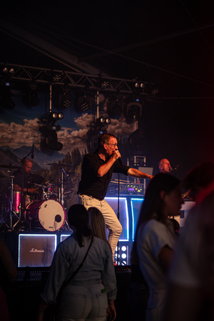 A man in a black shirt performs on stage with a guitar.