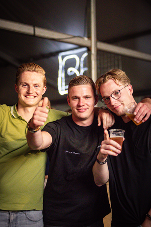 Three men pose together, smiling and giving thumbs up signs.