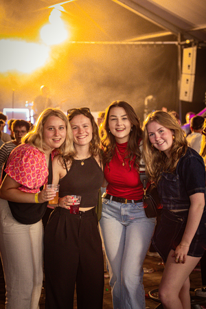 Four women posing for a photo with one holding a drink.