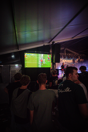 A group of people are watching a football match on the TV.