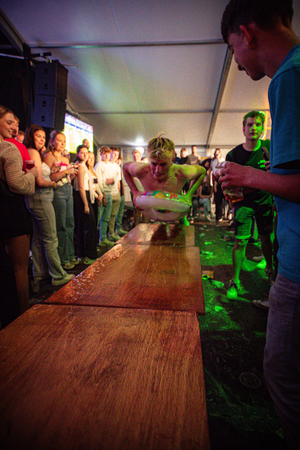 A man in a blue shirt stands at the back of a line as people are served drinks.