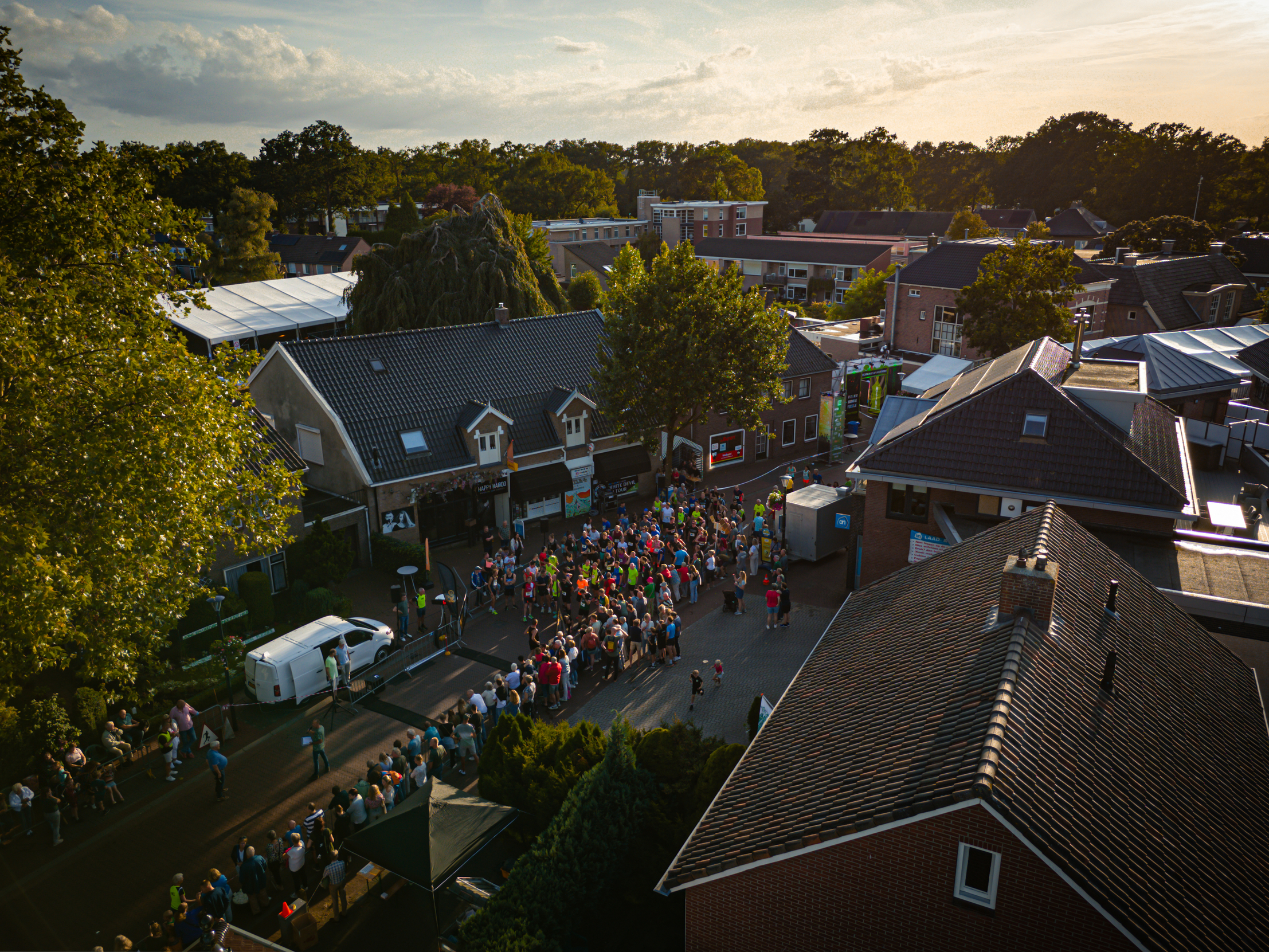 A small group of people standing together, with a tree and buildings in the background.