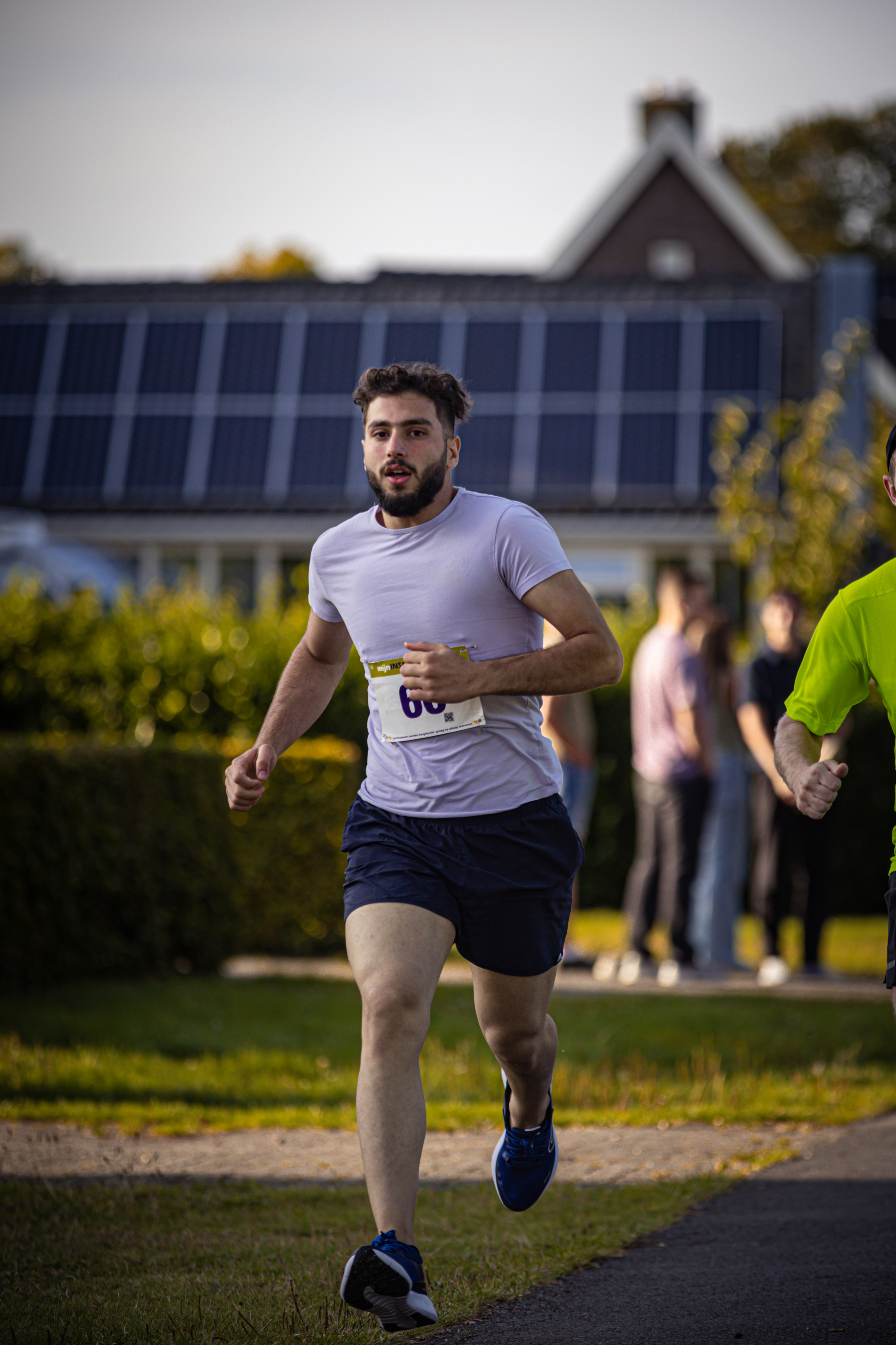 A man in a blue and white shirt running on a street with a number 8 on his chest.