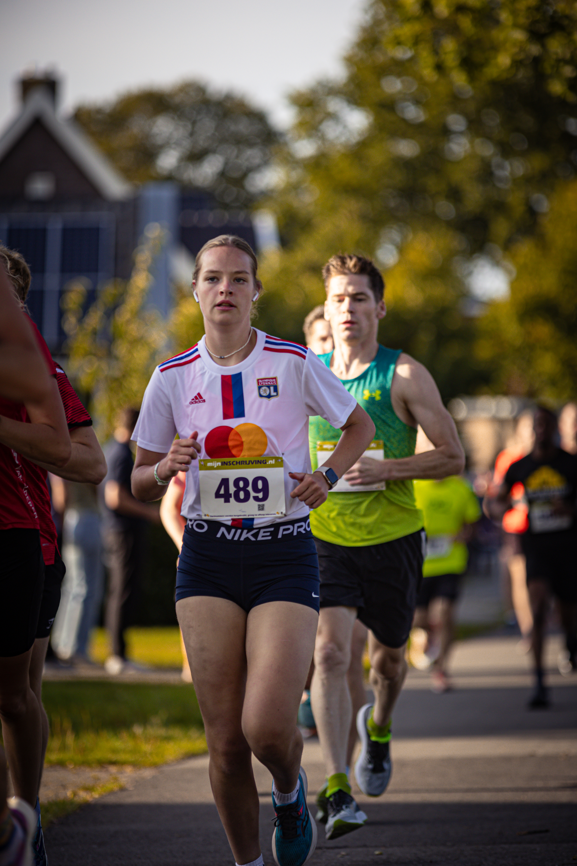 "Four people running on a road, one of whom is wearing the number 489.