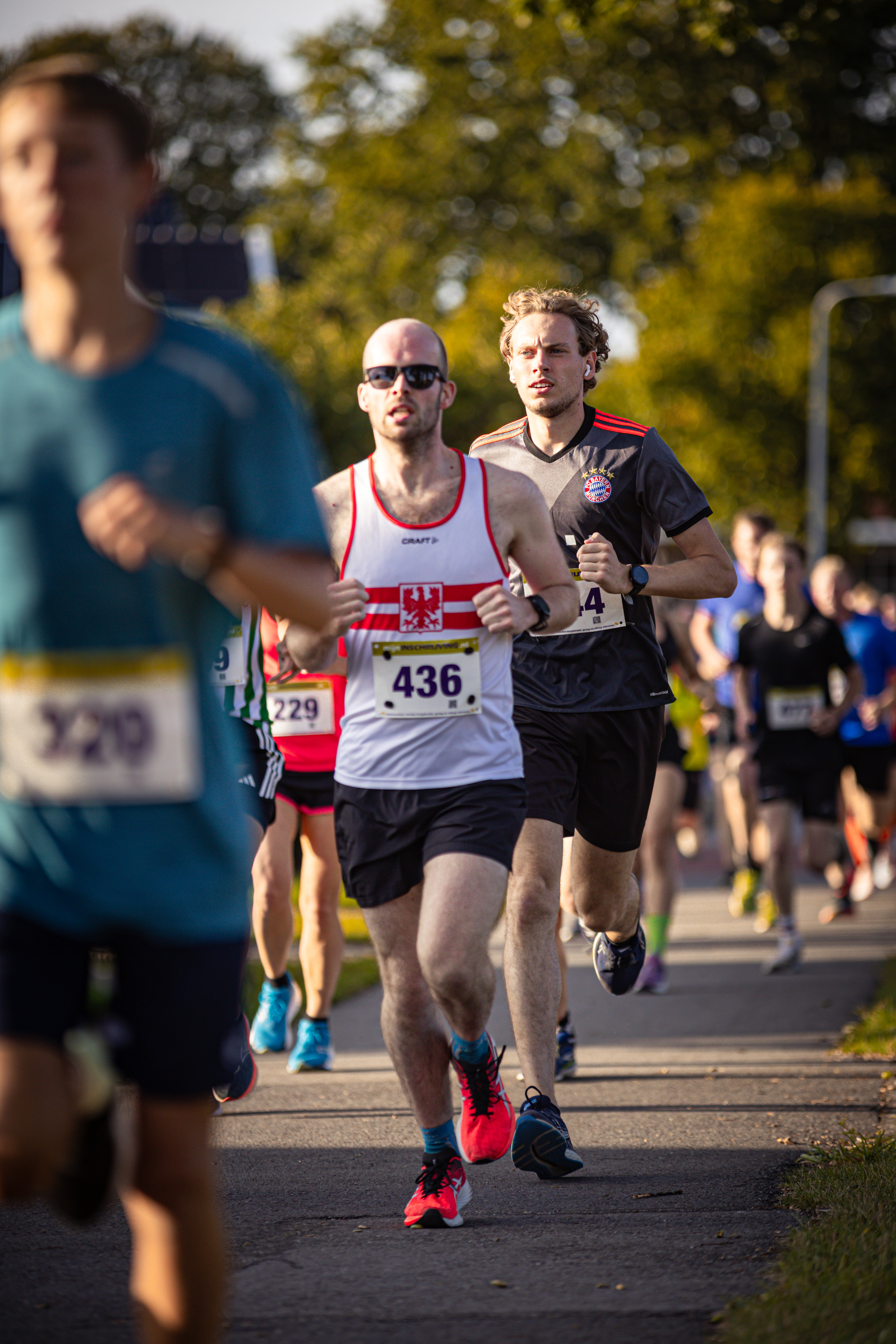 A group of runners on a street, with one runner wearing a bib with the number 426.