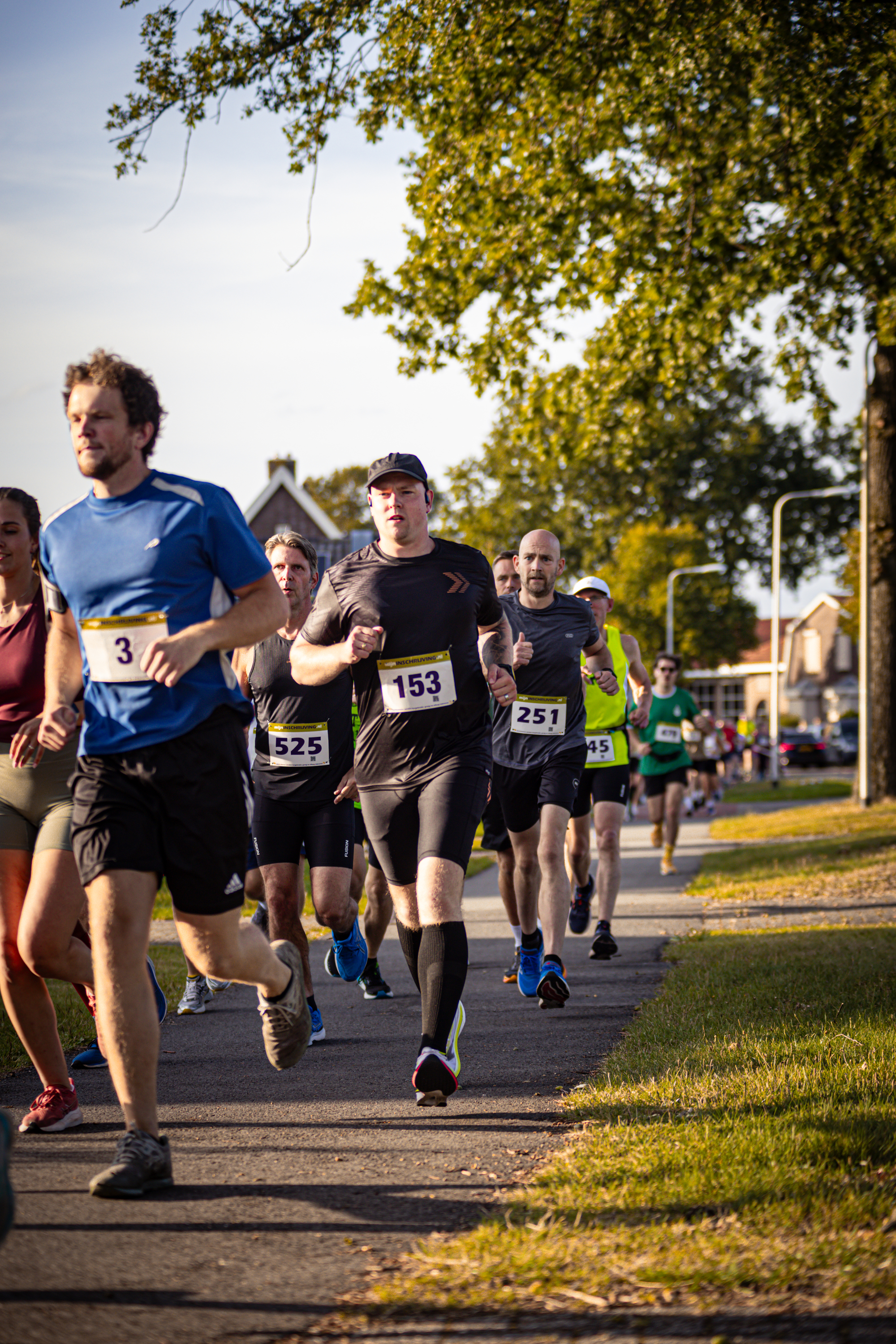 A group of runners are running on a road with one runner wearing number 199.