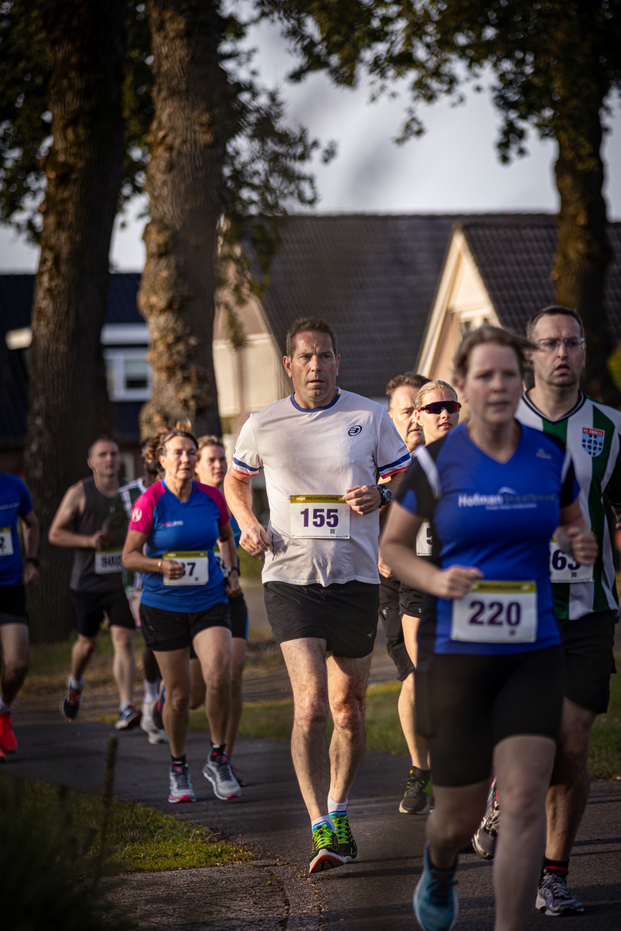 Several people are running a race wearing numbers and shirts.