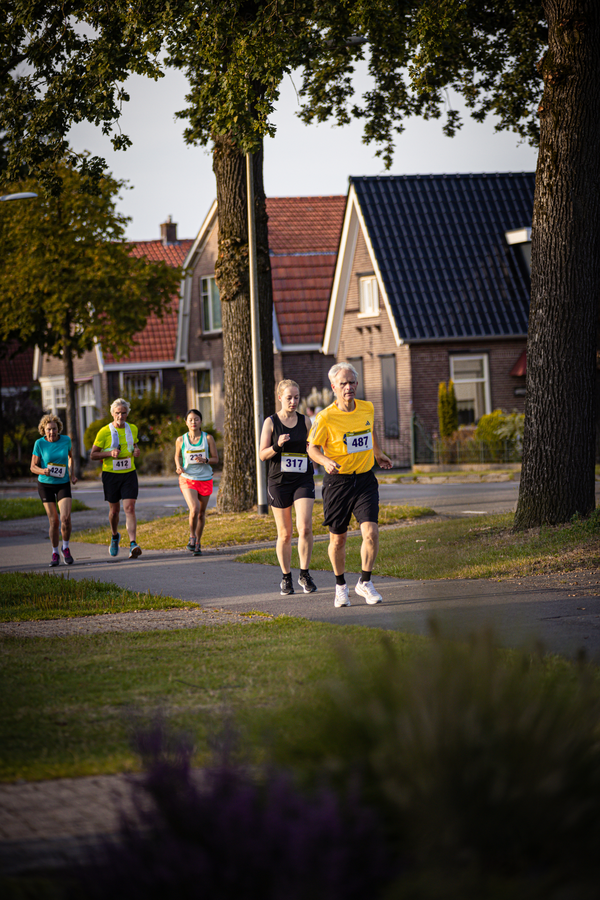 Three people running on a street in front of houses.