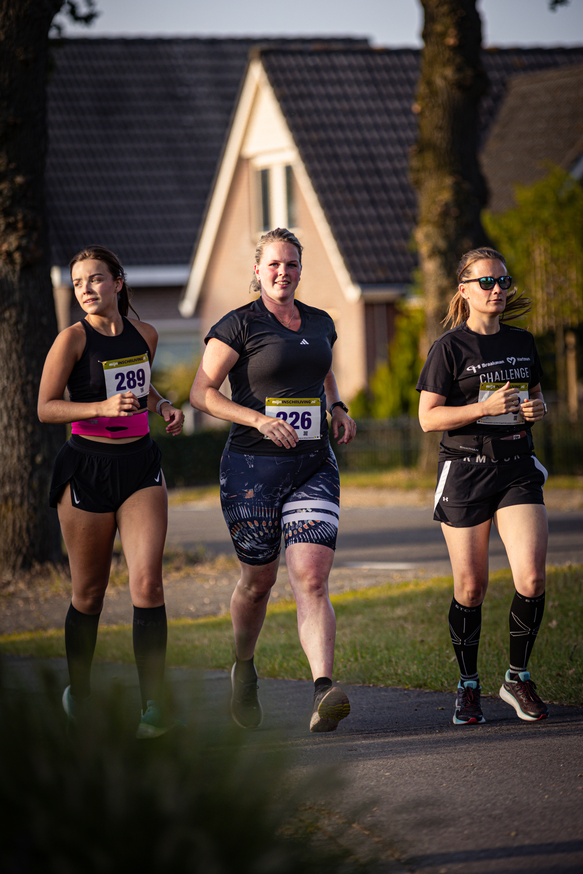 Three women running on a sidewalk, one with 29 on her shirt.