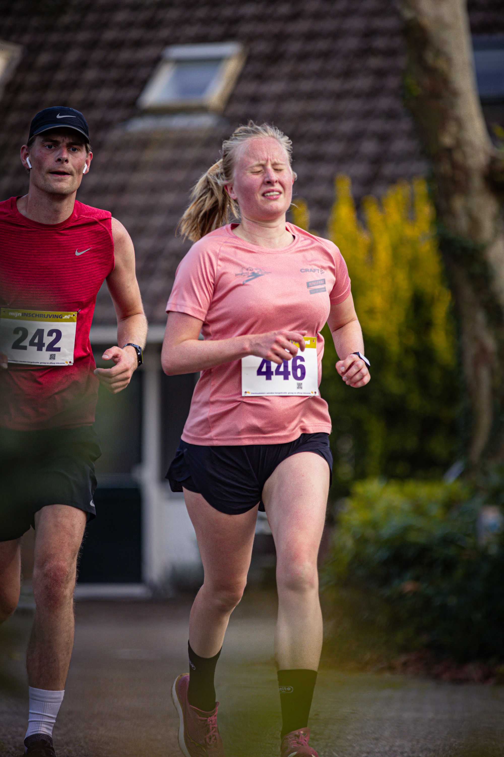 Two people are running on a trail. The person in the pink shirt is wearing number 416.