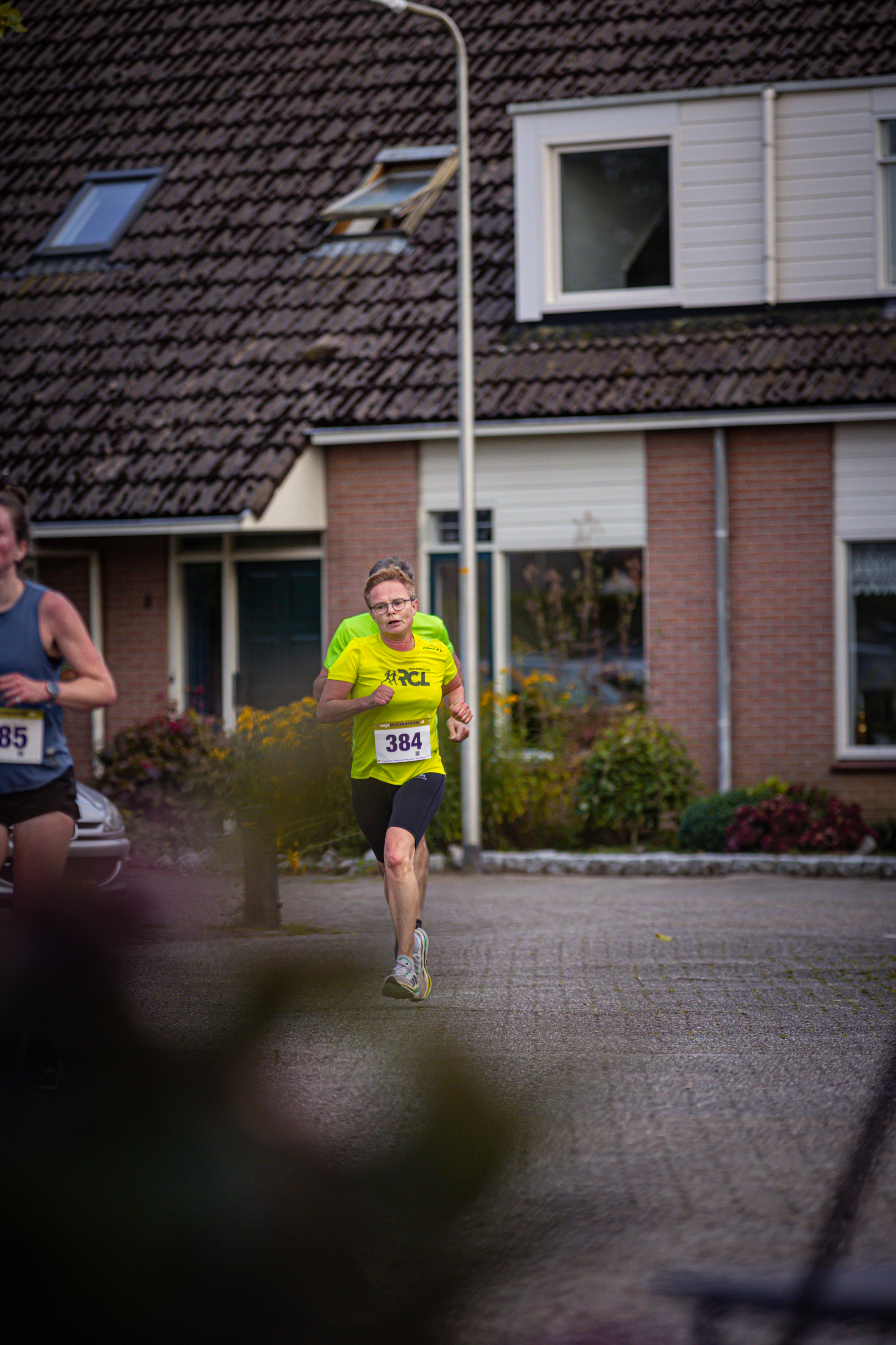 A man wearing a yellow shirt with the number 246 on it is running down a street.