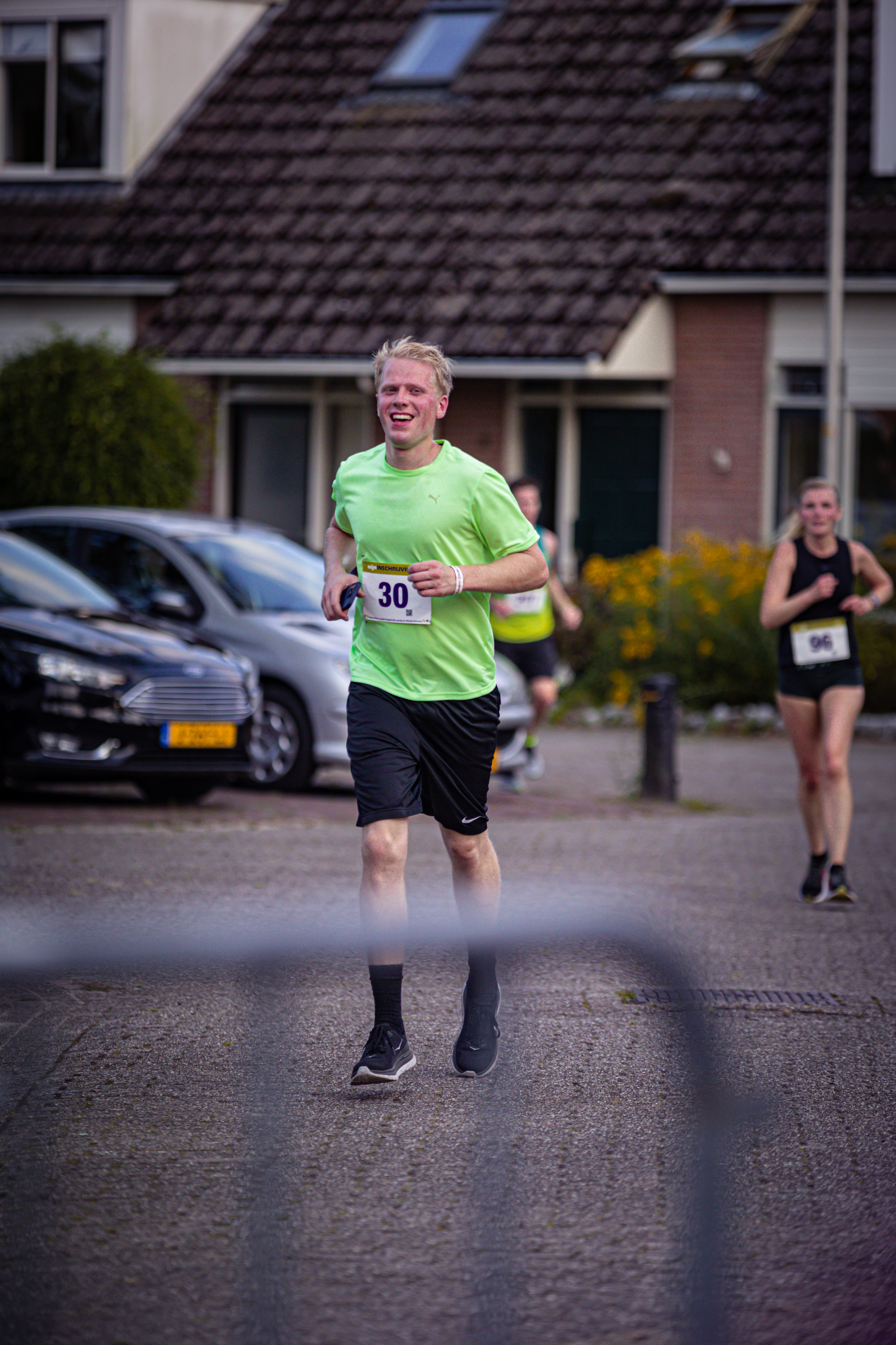 Two runners are in a race on the street in front of houses.