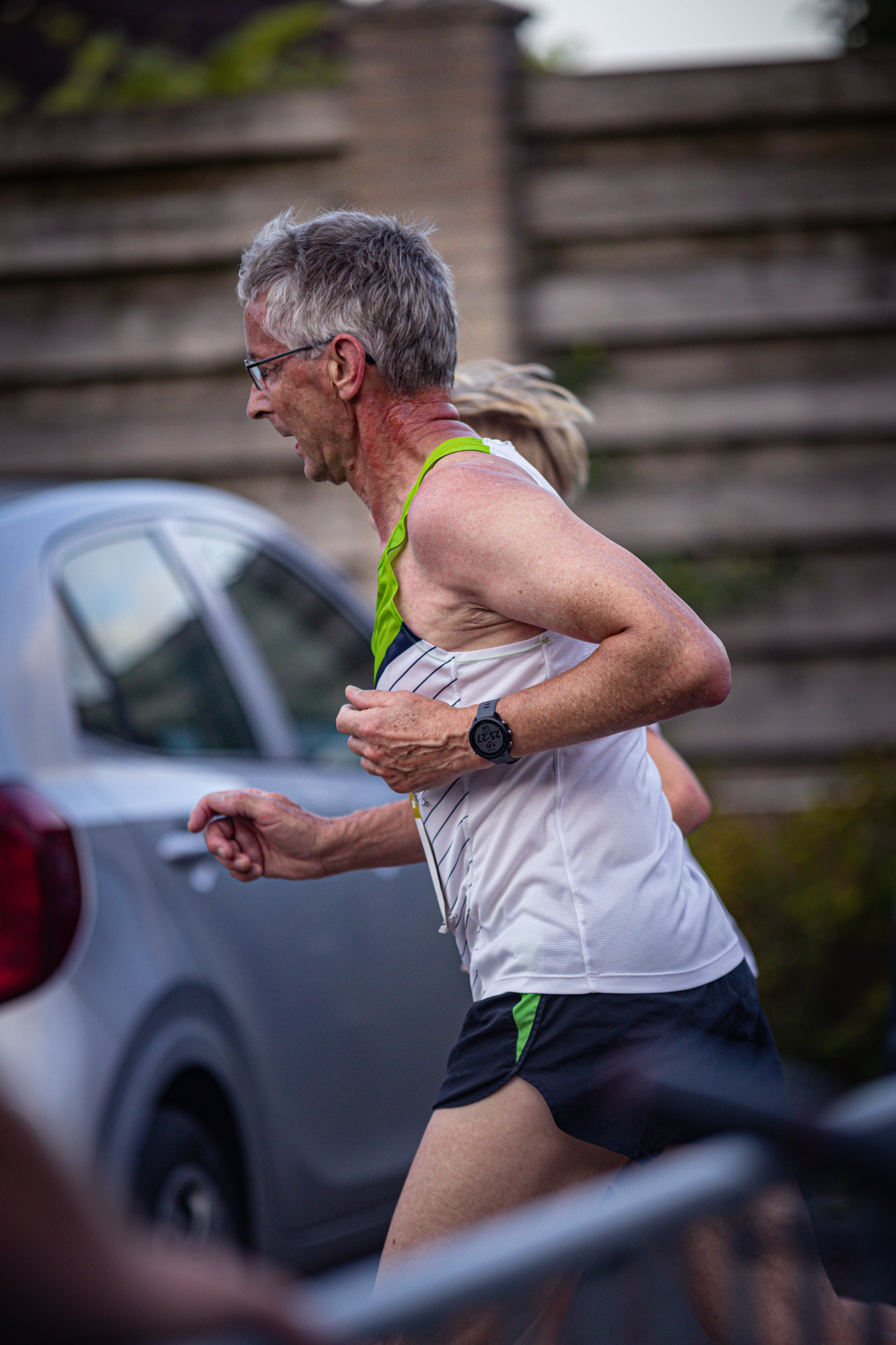 A man in a tank top and shorts runs down the road.