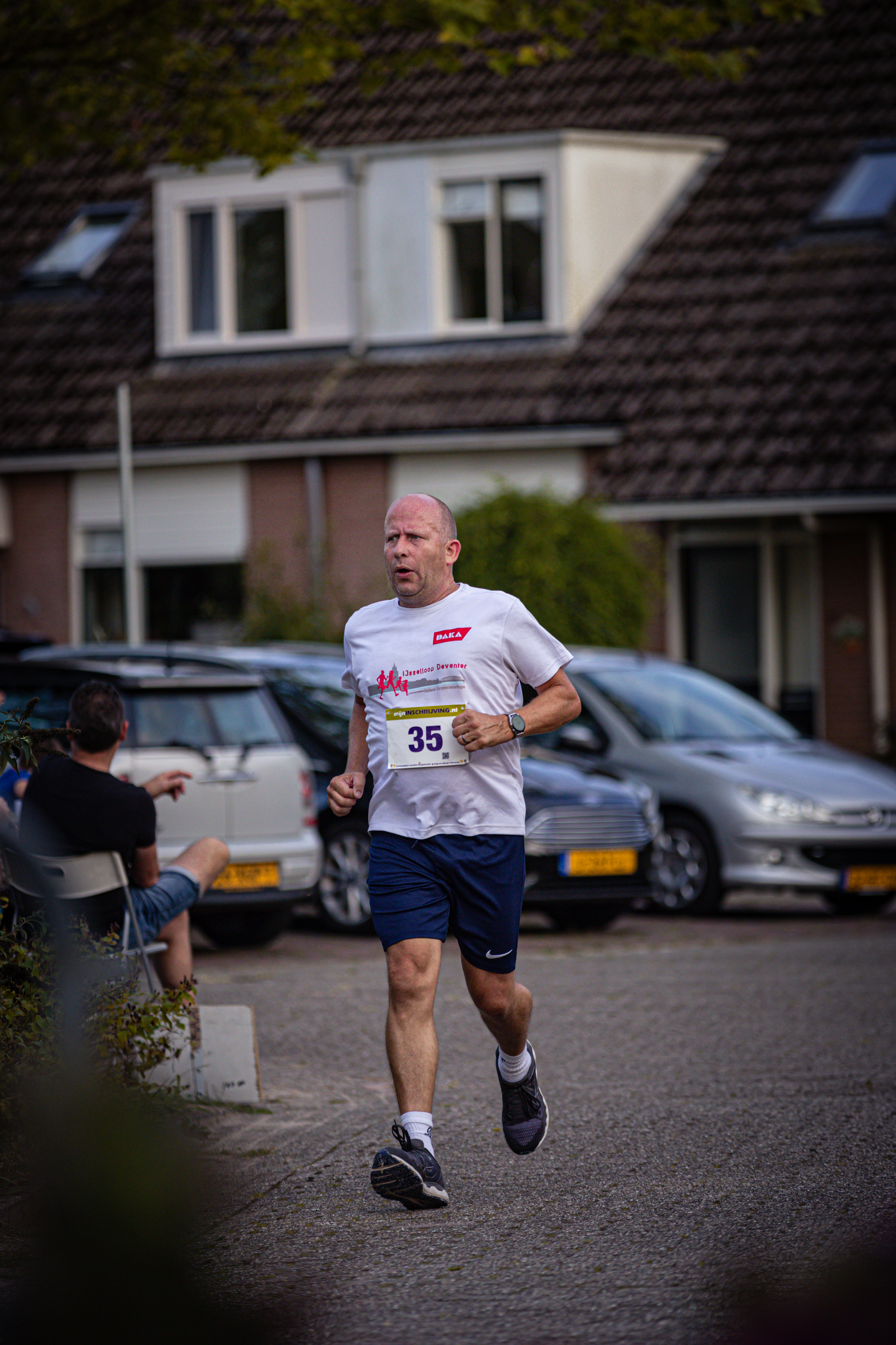 A man in a white shirt, bearing the number 39, runs on a street.