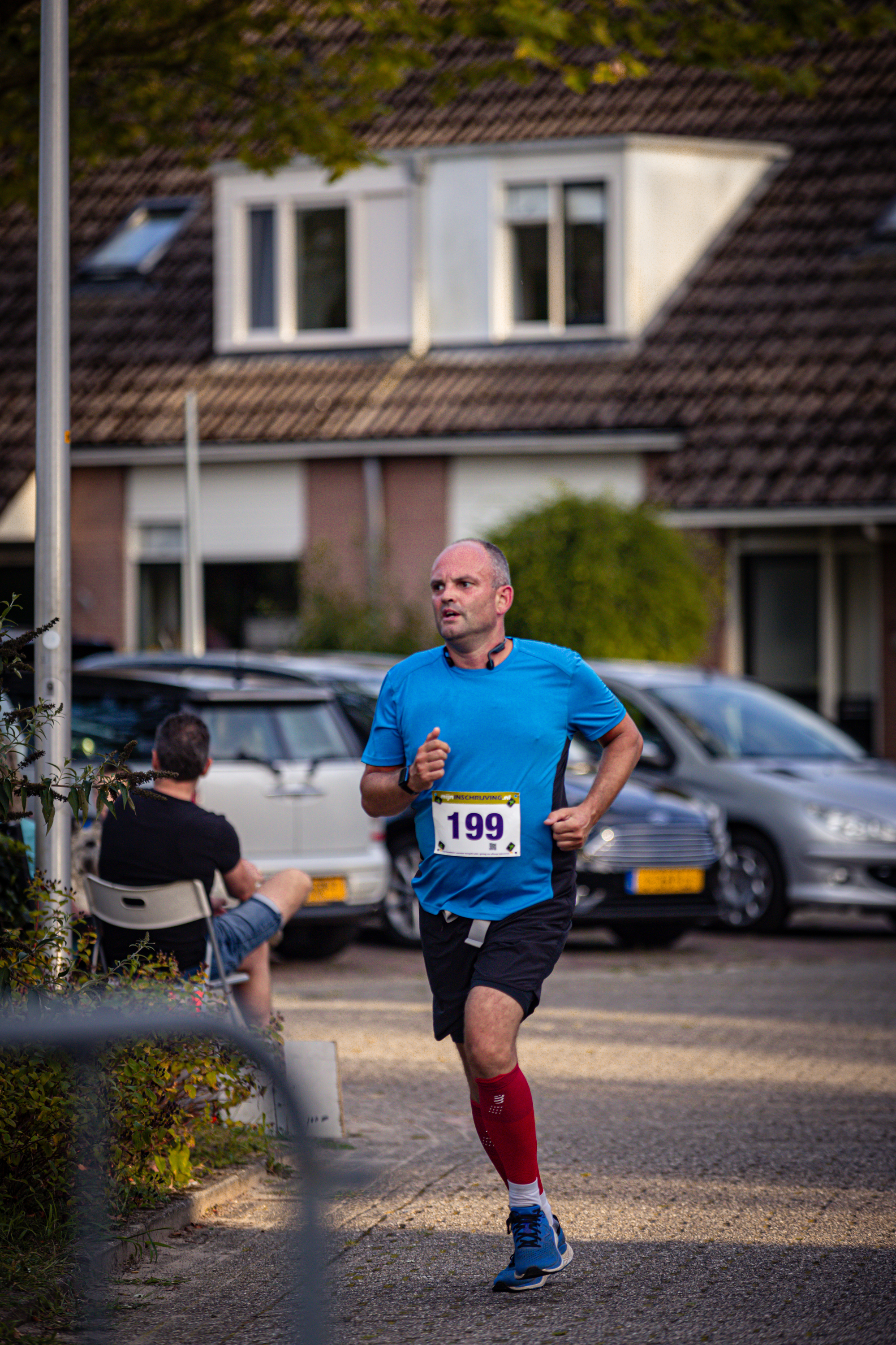 A man in a blue shirt and red socks runs on the street, wearing number 139.