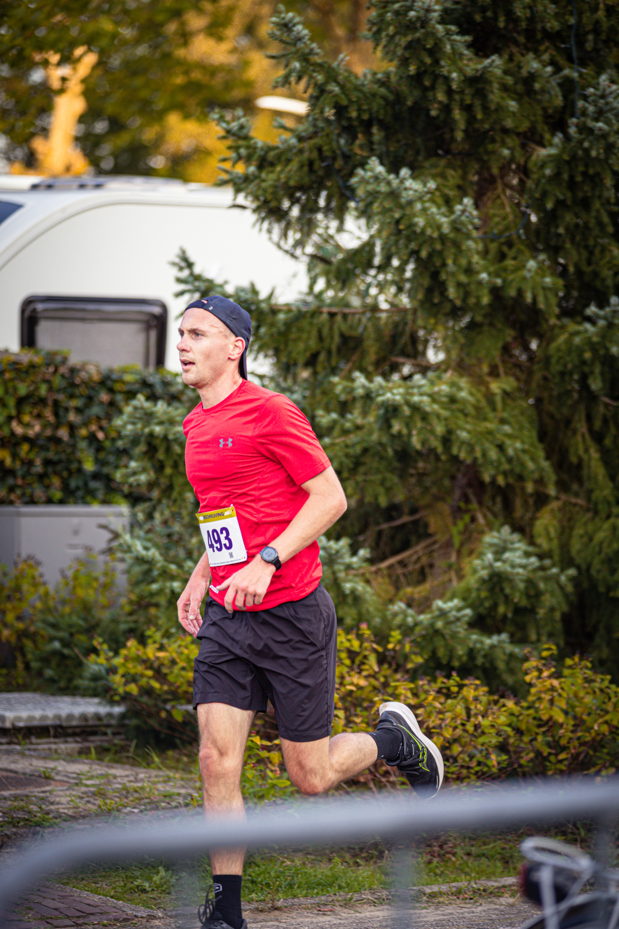 A man in a red shirt and shorts runs down the street.