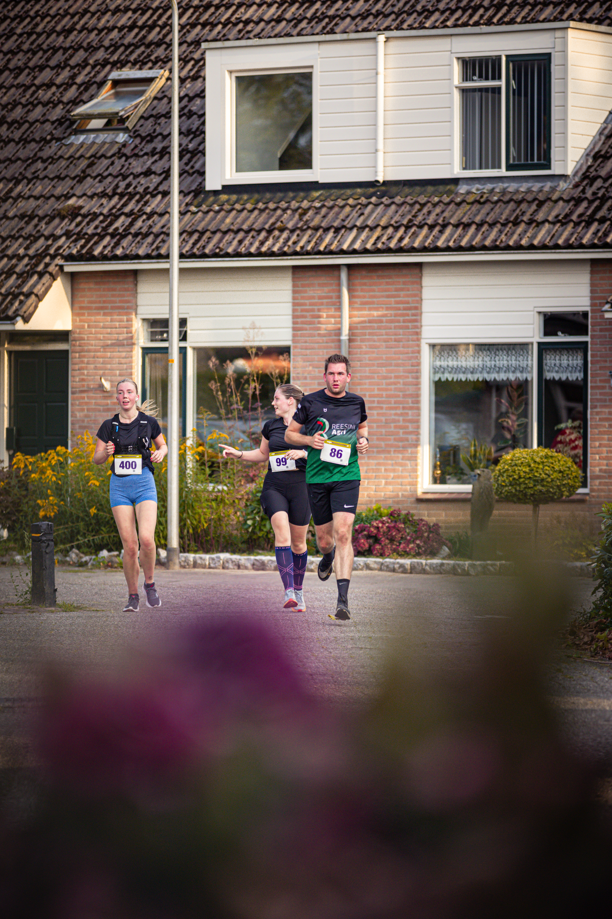 A group of people running down a street with one wearing a black shirt and number 22.