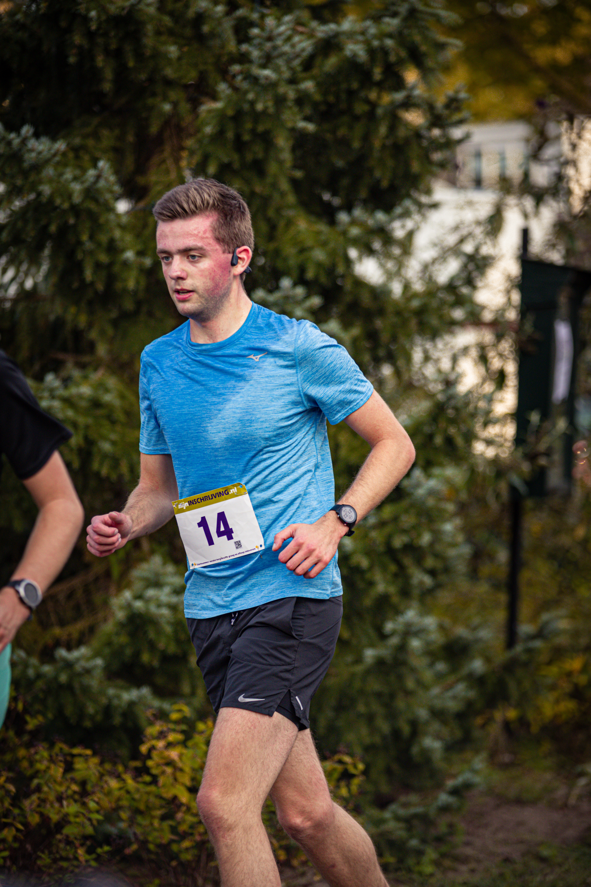 A man running with a blue shirt and the number 14 on his.