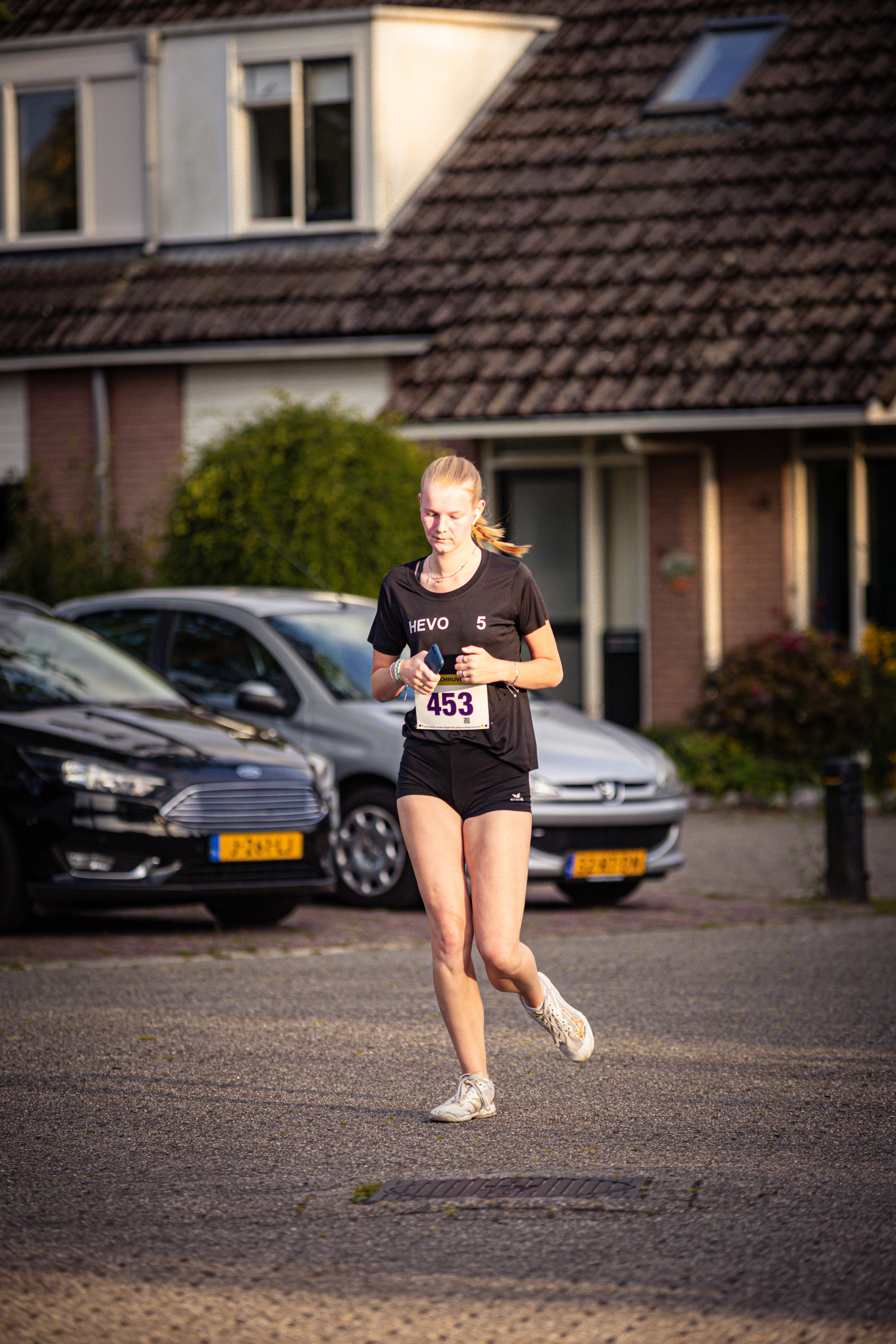 A woman running in the street with a number 439 on her shirt.