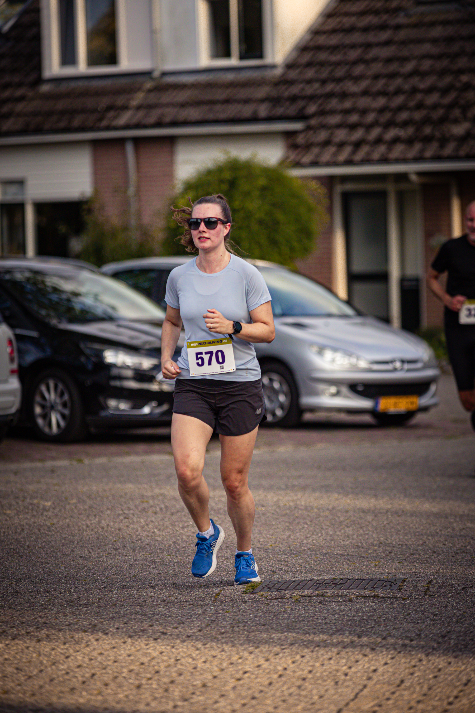 A woman running in the street with the number 579 on her back.